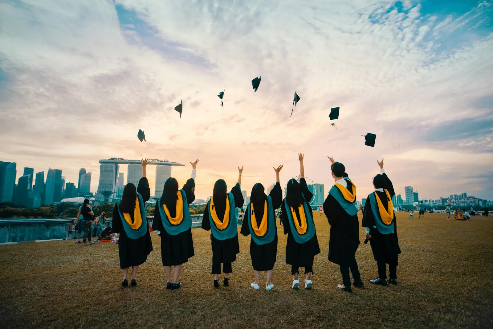 Graduates throwing their caps against a city skyline