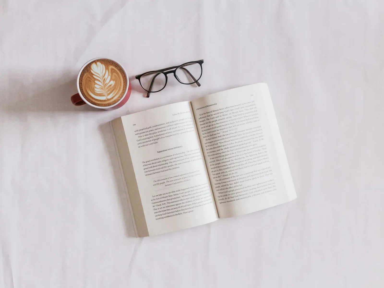 An open book and reading glasses on a desk